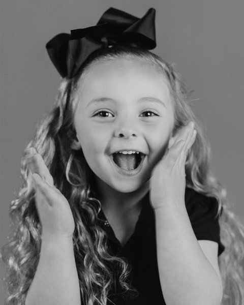 joyful black and white school portrait of a girl with a black bow, Denver